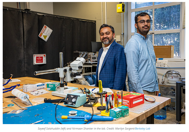 Men standing in front of a table with a microscope

Description automatically generated